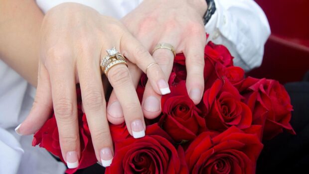 Hands wearing wedding rings over a bouquet of red roses symbolizing love, HD Desktop Wallpaper