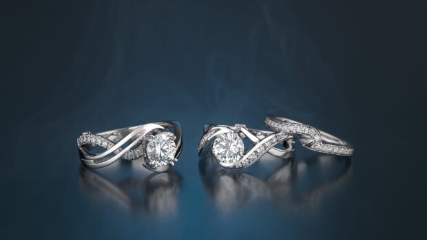 Two diamond wedding rings with detailed engravings on a reflective surface, 2K Desktop Wallpaper