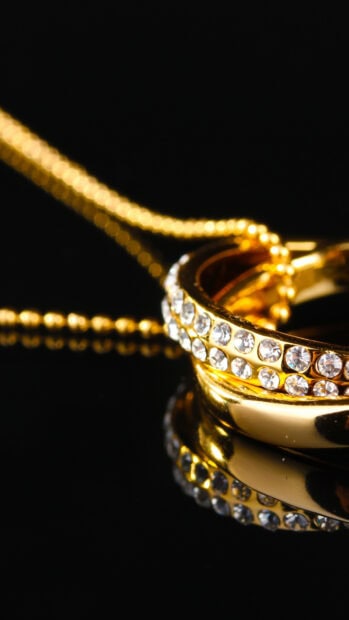 A close up of elegant gold rings adorned with sparkling diamonds on a dark surface, HD Mobile Wallpaper
