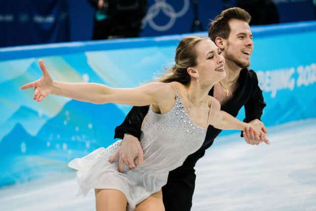 A smiling ice dancing couple gracefully glides across the rink during a competition, HD Desktop Wallpaper
