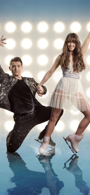 A couple is ice dancing together on an ice rink with bright lights behind them, 2K Phone Wallpaper