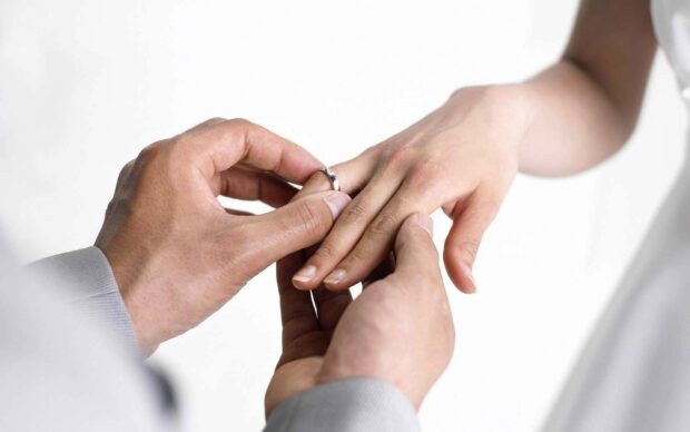 A person gently puts a wedding ring on another hand during the ceremony, 2K Desktop Wallpaper