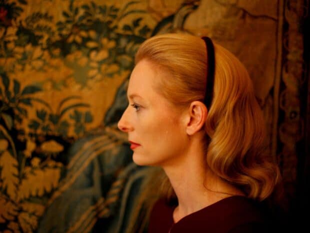 A side profile of Tilda Swinton wearing a headband with a decorative background, HD Desktop Wallpaper