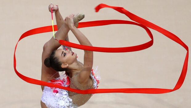 A rhythmic gymnastics athlete performs an impressive ribbon routine showing flexibility and grace, HD Desktop Wallpaper