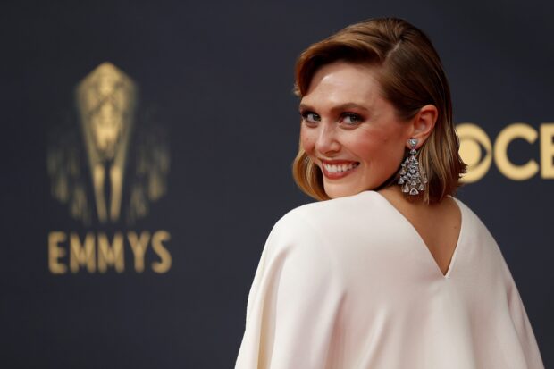 A woman smiles elegantly at the Emmy Awards event with the logo in the background, HD Desktop Wallpaper