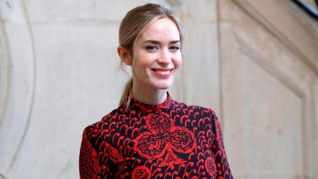 Emily Blunt Wallpapers shows a woman smiling warmly in a red and black patterned dress, HD Desktop Wallpaper