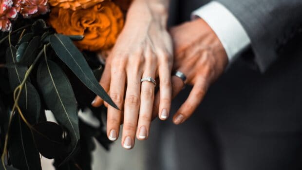A close up of wedding rings on the couple's hands with an orange flower and green leaves, 4K Desktop Wallpaper