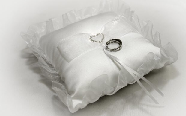 A pair of wedding rings rests on a satin pillow decorated with a small heart chain, HD Desktop Wallpaper