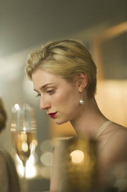 Elizabeth Debicki is seen looking down thoughtfully in a soft lit setting, 2K Mobile Wallpaper
