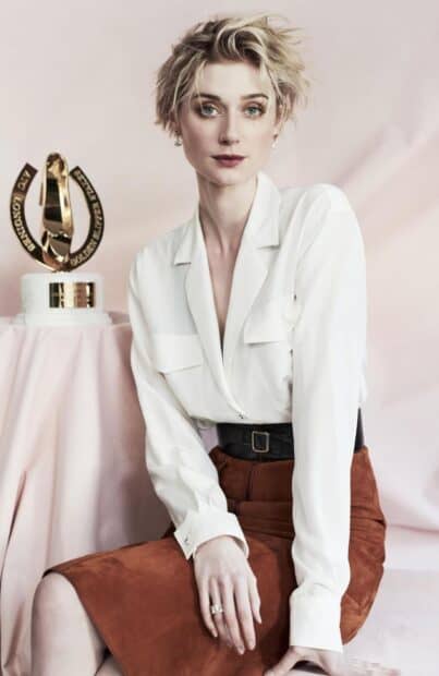 Elizabeth Debicki poses in a white shirt and brown skirt with a trophy in the background, HD Mobile Wallpaper