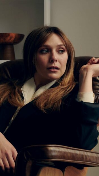 Elizabeth Olsen appears thoughtful sitting in a leather chair, 2K Phone Wallpaper