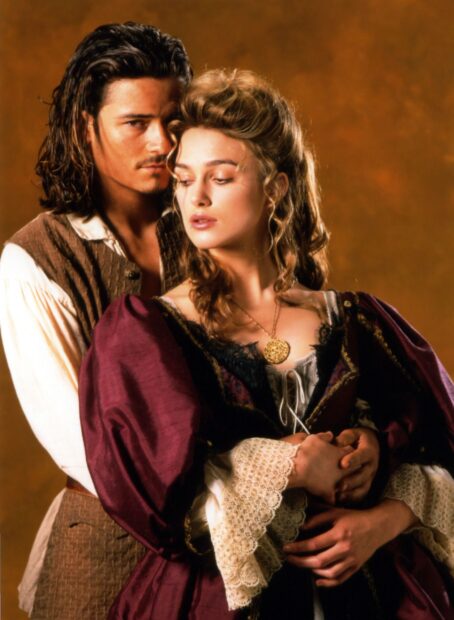 Elizabeth Swann in Pirates of the Caribbean stands with a man against a brown background, 2K Mobile Wallpaper