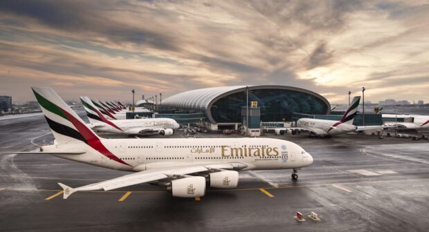 An Emirates Airbus A380 plane is parked at a busy airport terminal during sunset, 2K Desktop Wallpaper