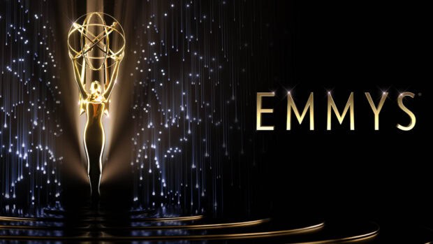 The Emmy Awards golden statue shines brightly on a dark stage with sparkling lights, 4K Desktop Wallpaper