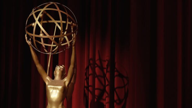 The Emmy Awards sculpture stands tall in front of a red curtain with dramatic lighting, HD Desktop Wallpaper