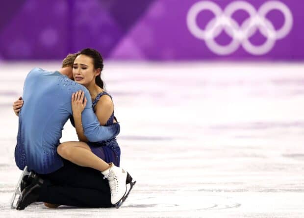 A pair of ice dancers share an emotional embrace on the Olympic ice rink, HD Desktop Wallpaper
