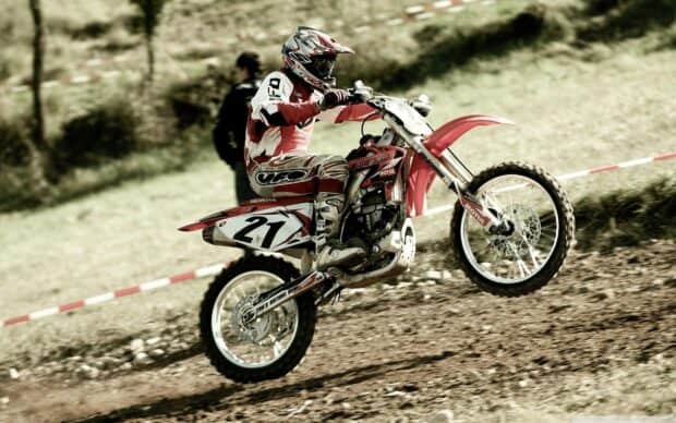 A rider is performing a wheelie on an enduro motorbike on a dirt track, 2K Desktop Wallpaper