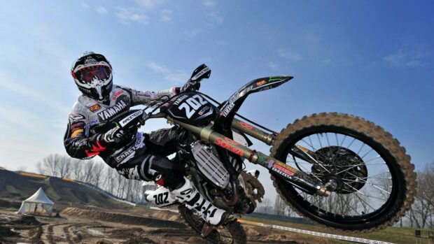 A motocross rider performing a jump on an Enduro motorbike during a race, 4K Desktop Wallpaper