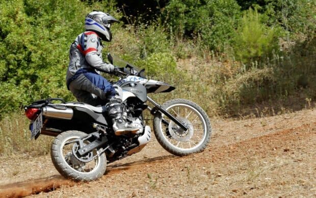 A rider is controlling an enduro motorbike on a dirt trail surrounded by trees, 2K Desktop Wallpaper