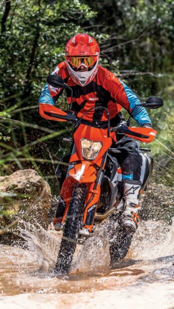 A rider on an enduro motorbike splashes through a muddy puddle on a forest trail, 2K Mobile Wallpaper