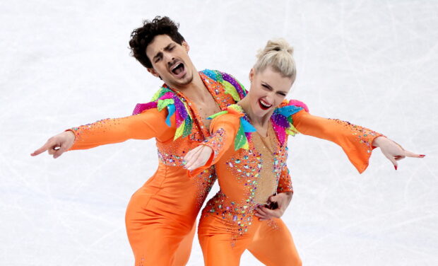 A male and female pair perform a dynamic ice dancing routine with colorful outfits, 2K Desktop Wallpaper