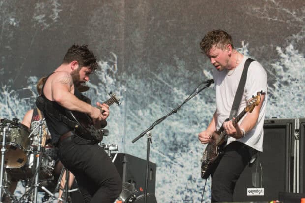Two Foals band members play guitar during an energetic live performance, 2K Desktop Wallpaper