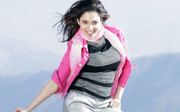 A joyful woman wearing a pink jacket is posing energetically outdoors, HD Desktop Wallpaper