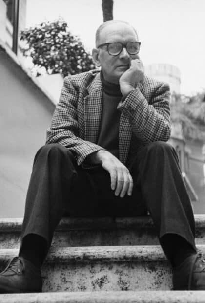 A classic black and white portrait of Ennio Morricone sitting on stairs with a thoughtful expression, HD Mobile Wallpaper
