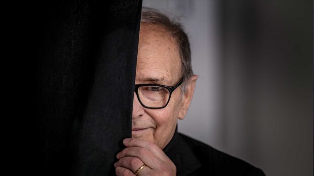 An elderly man wearing glasses is partially hidden behind a black curtain, holding it gently, HD Desktop Wallpaper