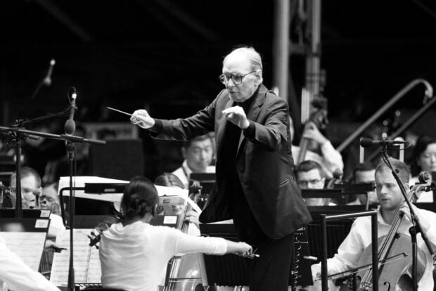 Ennio Morricone is passionately conducting an orchestra during a live performance, HD Desktop Wallpaper