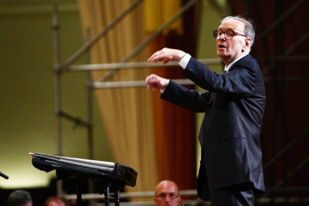 Ennio Morricone is seen conducting an orchestra during a live performance, HD Desktop Wallpaper