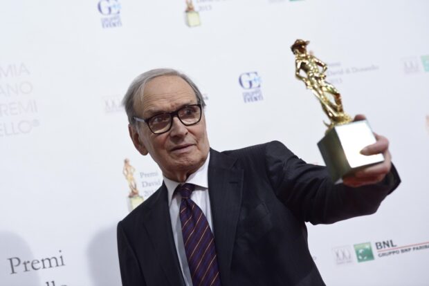 Ennio Morricone holding a statue at an award event wearing a suit and glasses, 2K Desktop Wallpaper
