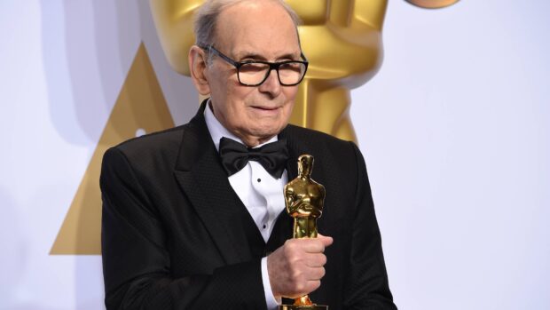 Ennio Morricone holding an Oscar statue at an award ceremony, 4K Desktop Wallpaper