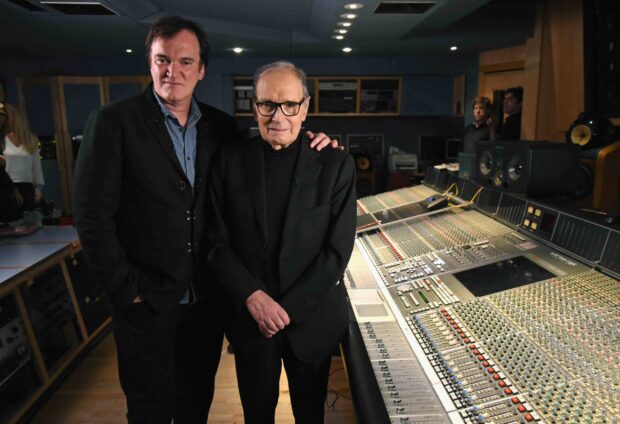 Ennio Morricone is standing with a man in a recording studio filled with mixing equipment, 2K Desktop Wallpaper