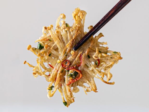 A close up of enoki mushrooms cooked with chili and herbs held by chopsticks, HD Mobile Wallpaper
