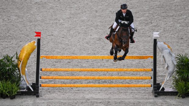 A rider is jumping a horse over a colorful obstacle in an eventing competition, 2K Desktop Wallpaper