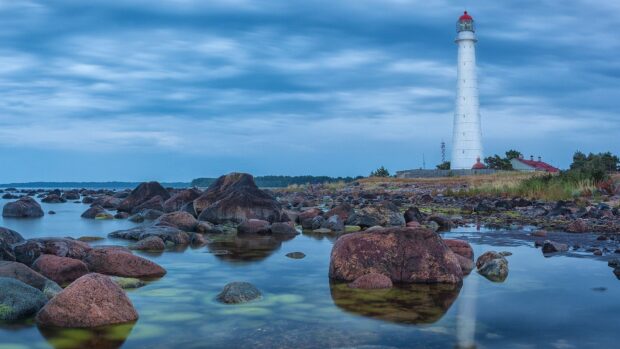 The Estonia coast features a tall white lighthouse surrounded by rocky waters under a cloudy sky, HD Desktop Wallpaper