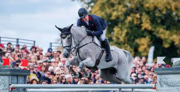 A rider on a horse is jumping over an obstacle in an eventing competition with spectators watching, HD Desktop Wallpaper