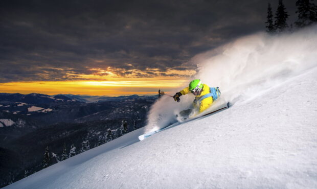 A skier is carving through fresh snow on a steep mountain slope at sunset, HD Desktop Wallpaper