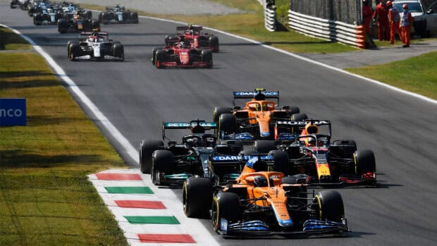 A group of F1 race cars competing closely on a race track during a sunny day, HD Desktop Wallpaper