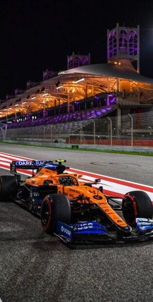 An F1 race car is speeding along the illuminated track under the night sky, HD Mobile Wallpaper