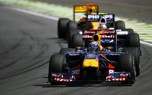 Two F1 Race cars racing closely on the track during a competitive event, HD Desktop Wallpaper