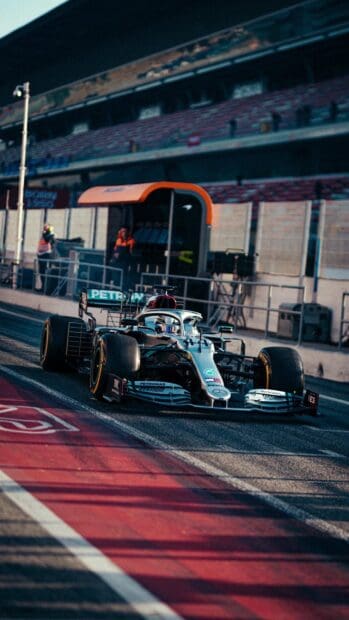 An F1 race car is driving on the pit lane during a race event, showcasing speed and precision, HD Phone Wallpaper