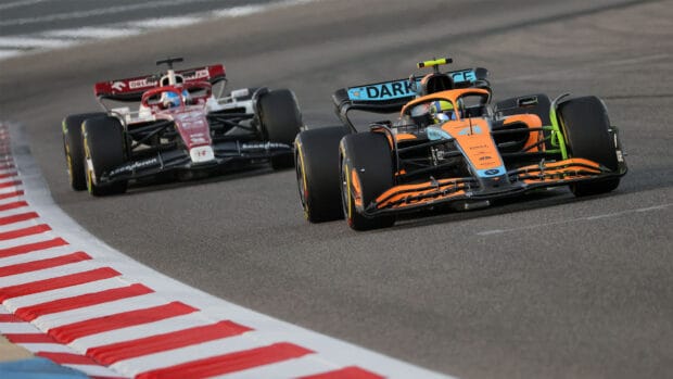 Two F1 race cars are speeding closely on the asphalt during a competitive race, HD Desktop Wallpaper