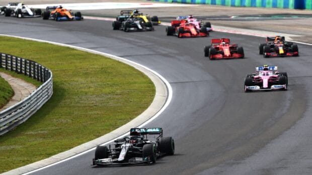 Several F1 race cars are navigating a wet circuit during a competitive race event, HD Desktop Wallpaper