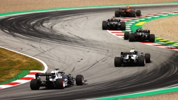 Several F1 race cars are navigating a sharp turn during the race on a professional circuit, HD Desktop Wallpaper
