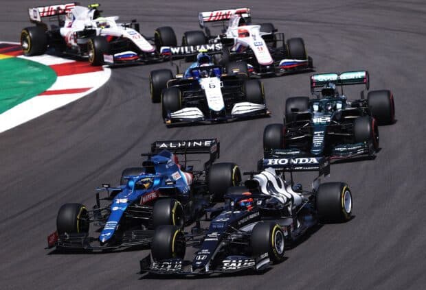 A group of F1 race cars taking a sharp turn during a high speed competition, HD Desktop Wallpaper