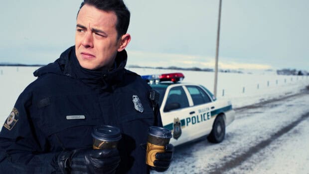 A Fargo police officer stands holding two coffee cups near a patrol car on a snowy road, HD Desktop Wallpaper