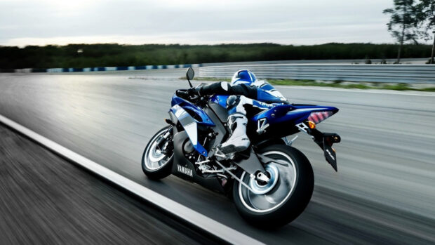 A blue Yamaha street bike is speeding on a race track with a rider in full gear, HD Desktop Wallpaper