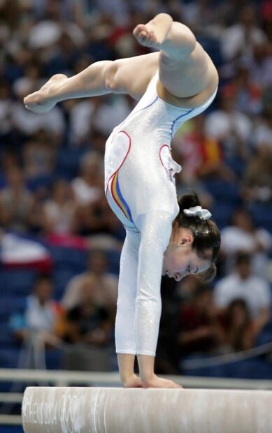 A female gymnast performs a handstand on the balance beam in acrobatic gymnastics, HD Mobile Wallpaper
